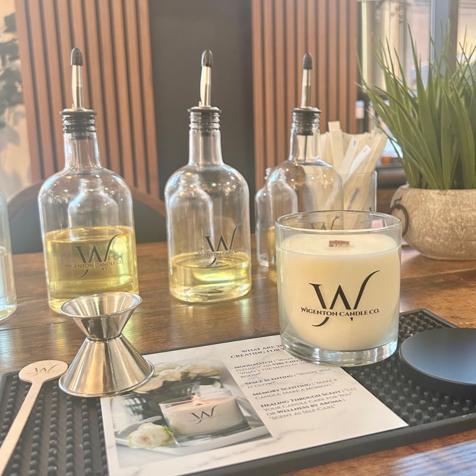 Wigenton Candle Co. candles and fragrance bottles on a table with a fragrance-making card underneath.