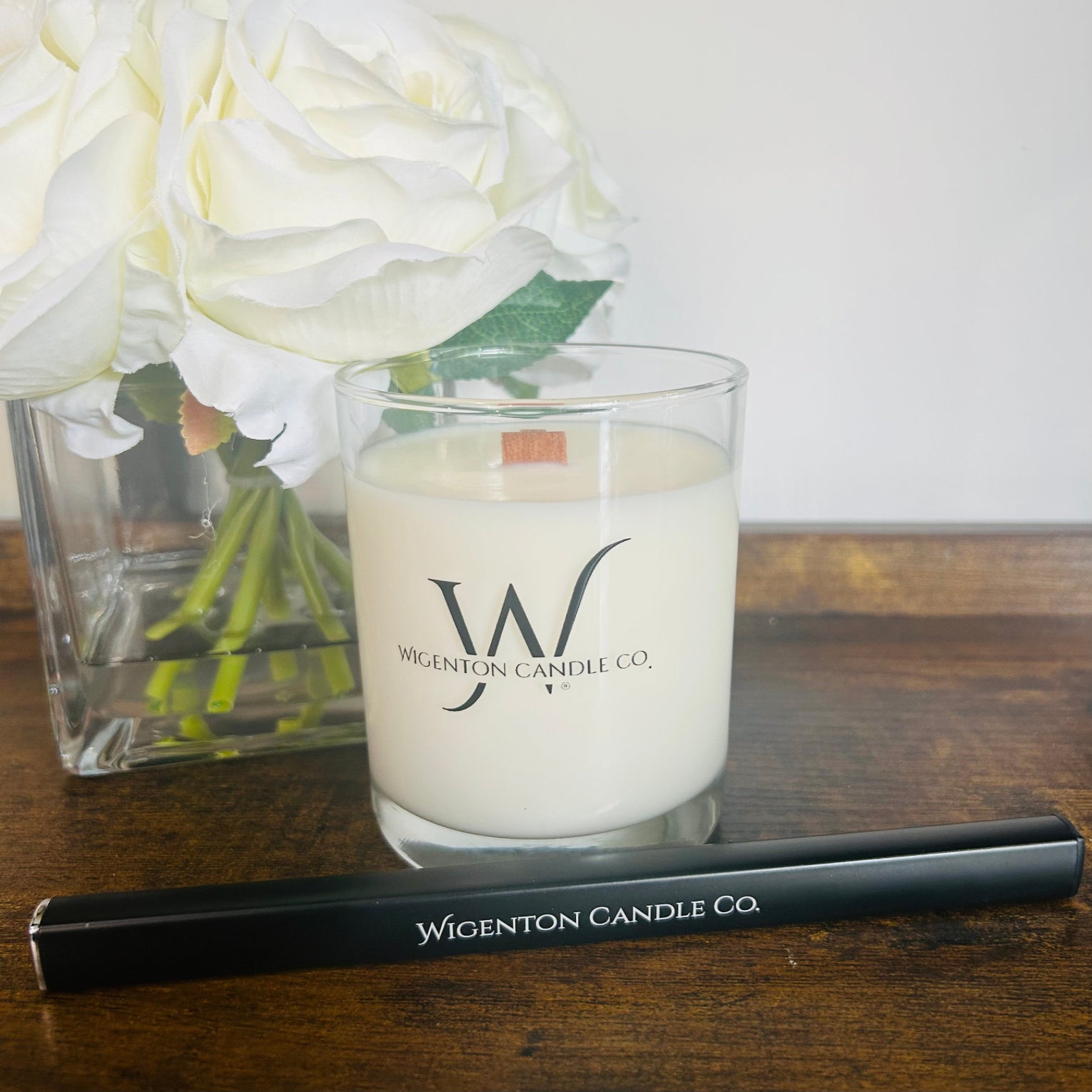 Wigenton Candle Co. candle electric lighter on a wooden surface with flowers in the background