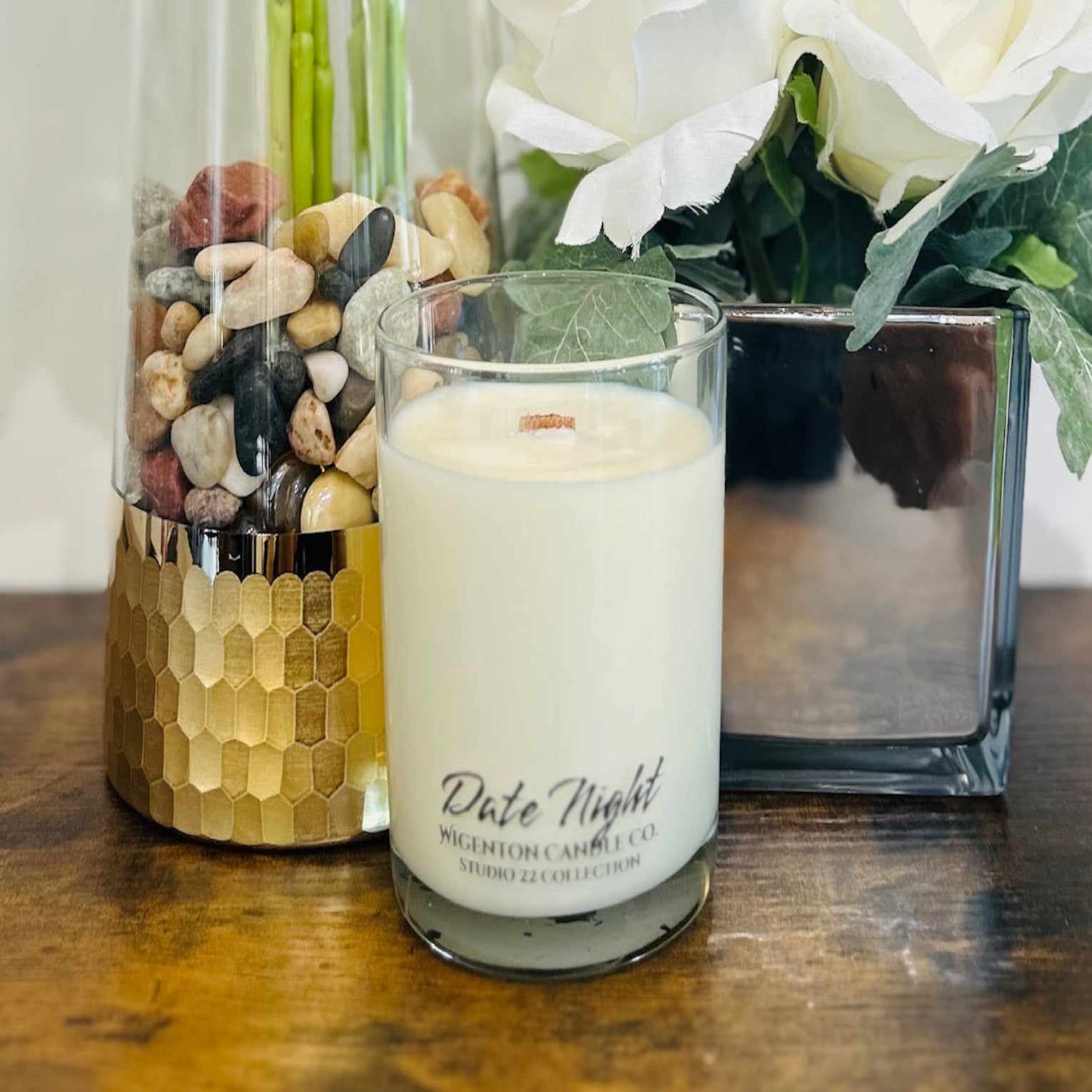 Candle labeled 'Date Night' with decorative stones and flowers on a wooden surface