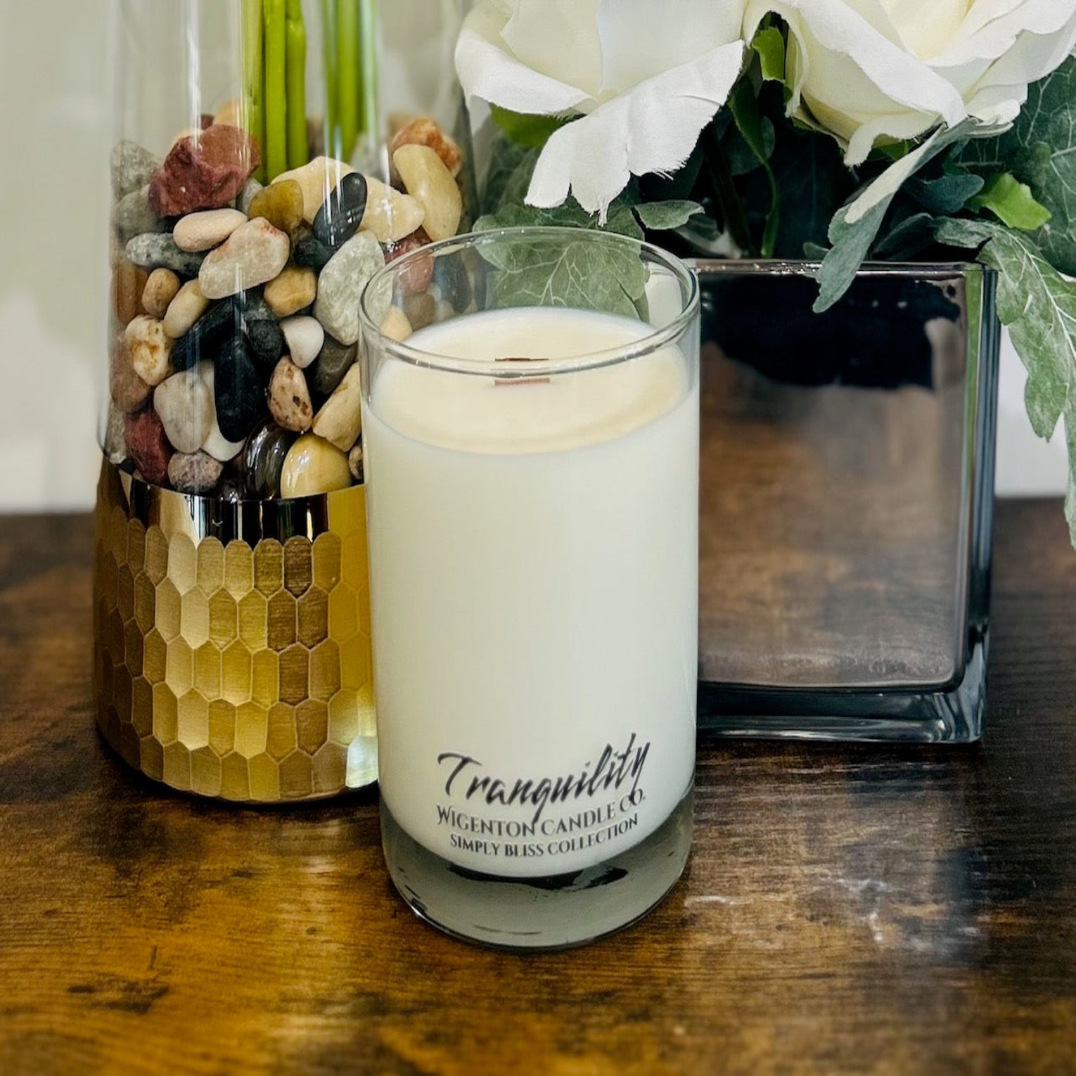 Candle labeled 'Tranquility' on a wooden surface with decorative elements.