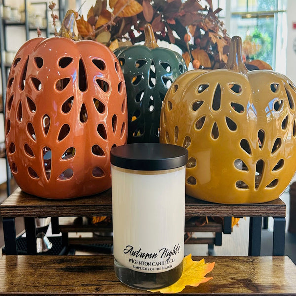 Candle labeled 'Autumn Night' with decorative ceramic pumpkins in the background.