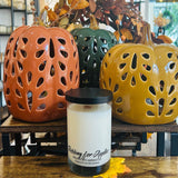 Candle with 'Bobbing for Apples' text in front of ceramic pumpkins on a wooden surface - Wigenton Candle Co. fragrance.