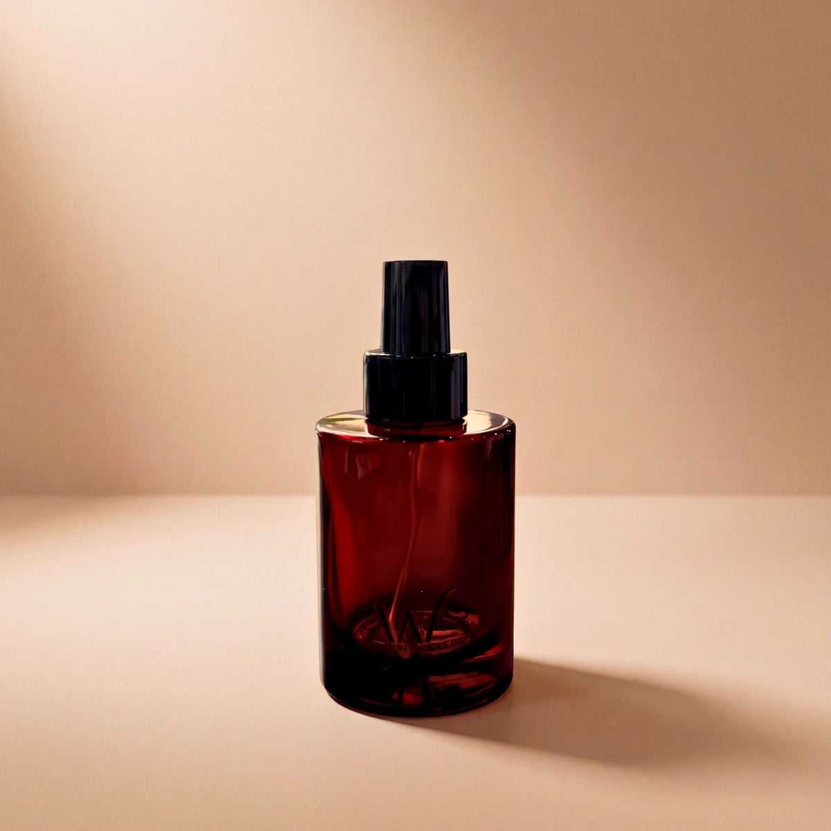 Wigenton Candle Co. 3.4 oz fragrance mist in an amber glass bottle with a black spray pump and W logo, displayed against a warm beige background.
