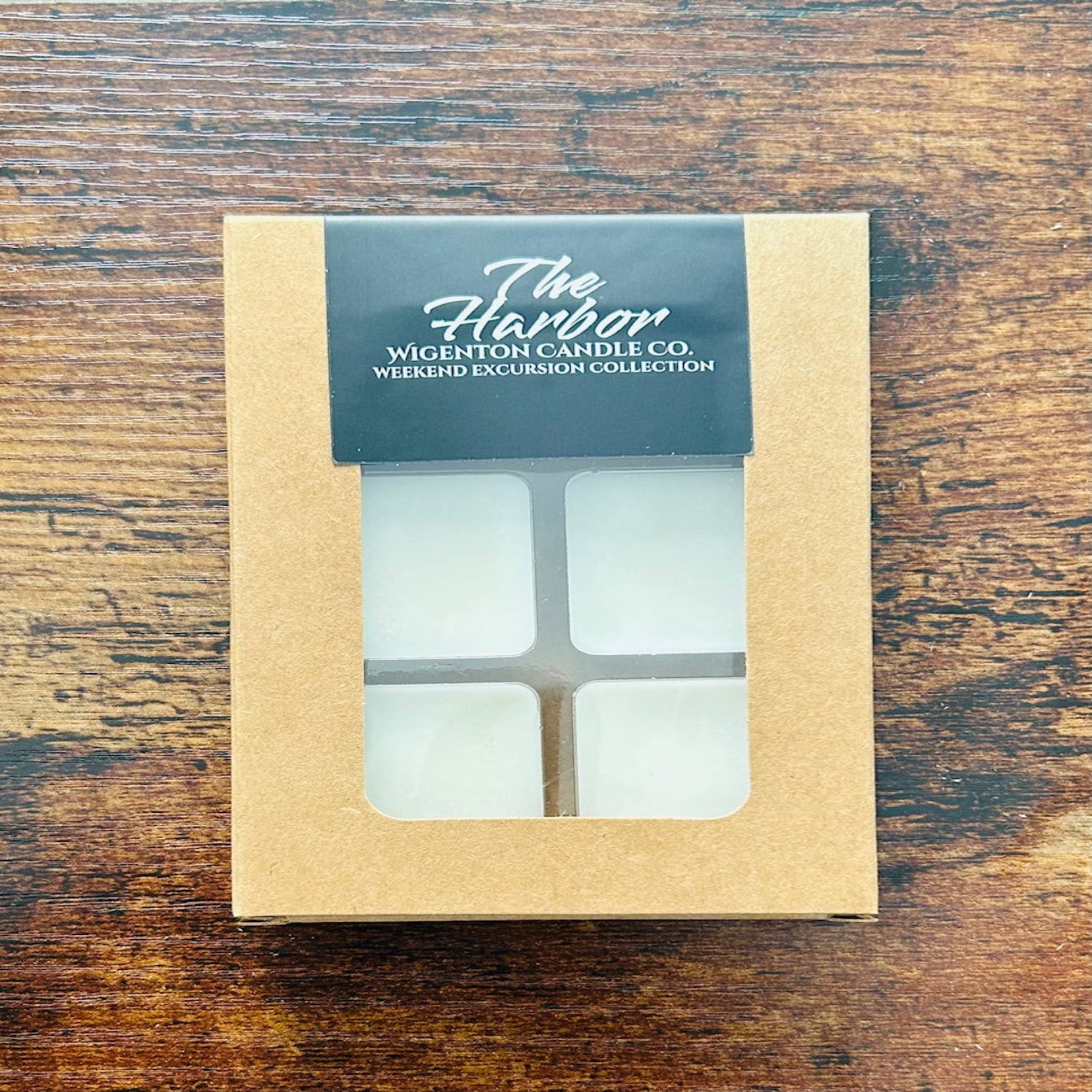 Candle packaging with 'The Harbor' label by Wigenton Candle Co. on a wooden surface