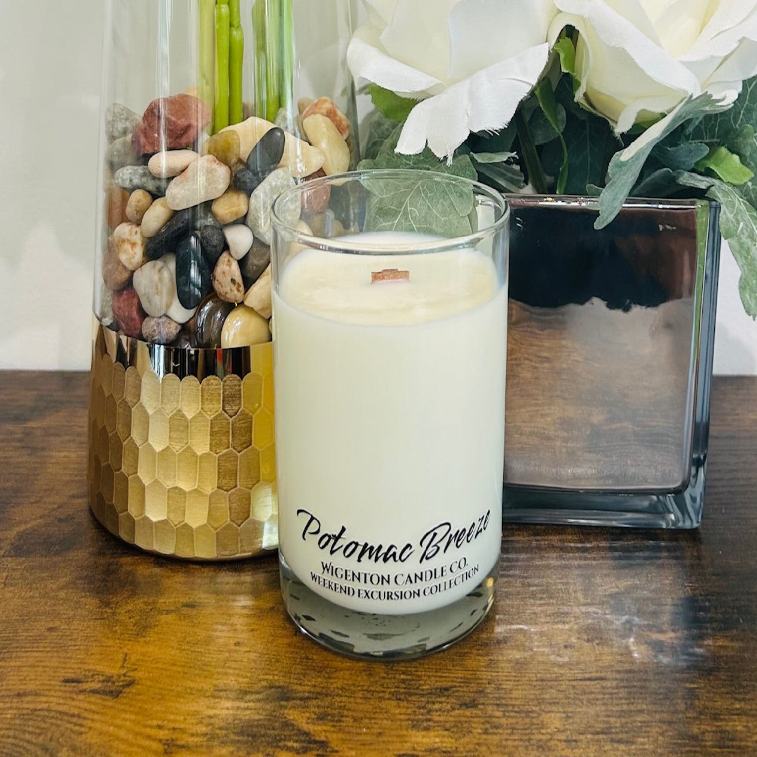 Soy Candle with Potomac Breeze branding in a glass container on a wooden surface, surrounded by decorative elements.