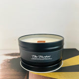 Candle in a black tin labeled 'The Harbor' by Wigenton Candle Co. on a wooden surface with a white background.