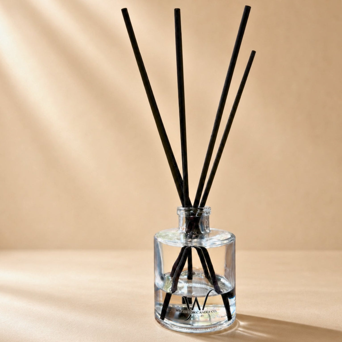 Clear Wigenton Candle Co. reed diffuser 5 oz with black reeds on a warm neutral background.
