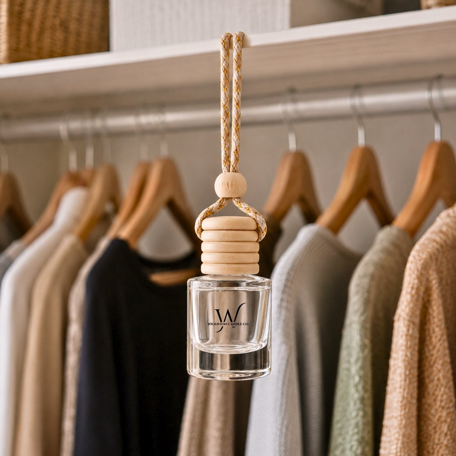 Hanging car and closet diffuser by Wigenton Candle Co. featuring a wooden cap and glass vessel, displayed in a wardrobe closet with clothing on hangers.