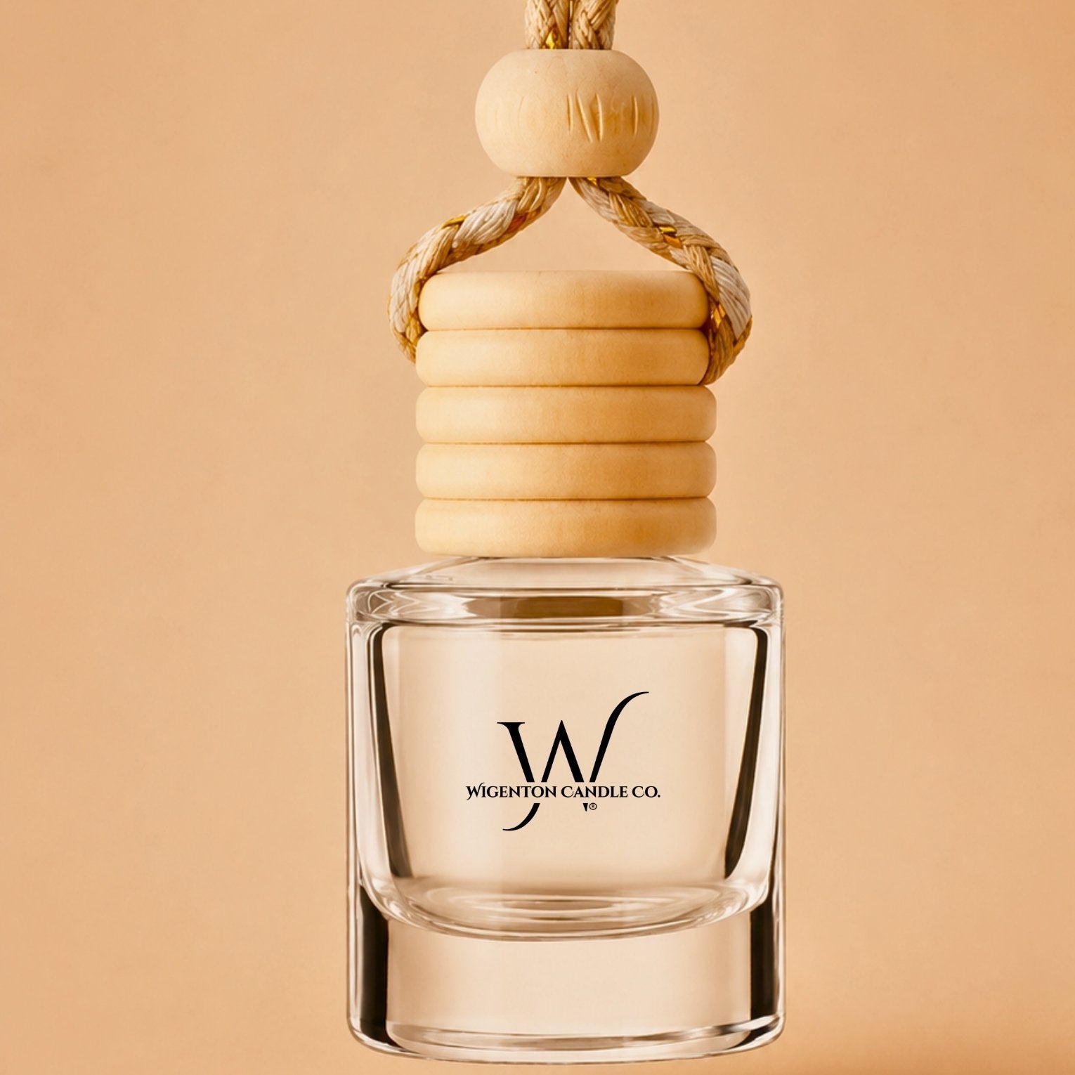 Wigenton Candle Co. hanging car diffuser with wooden cap and clear glass vessel on a warm beige background.