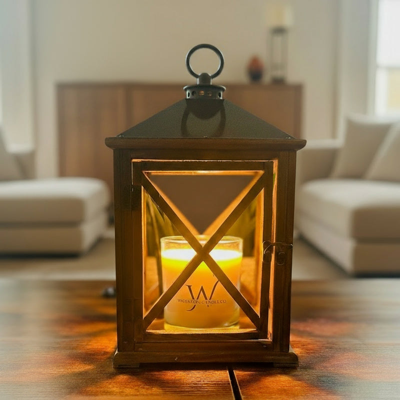 Wooden lantern with softly glowing candle on a wooden table in a cozy living room, background simplified for a clean, elegant look