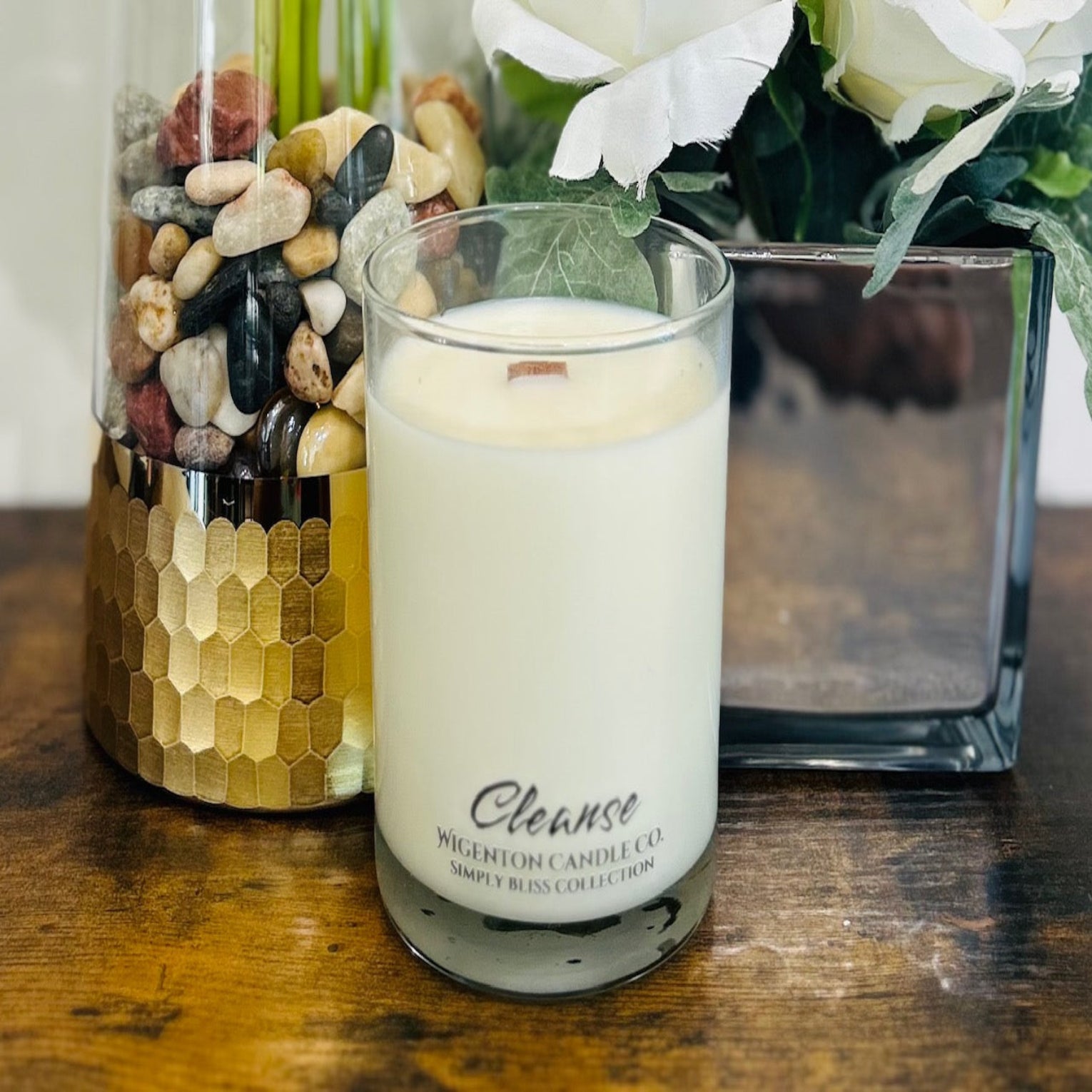 Soy Candle labeled 'Cleanse' with decorative stones and flowers on a wooden surface