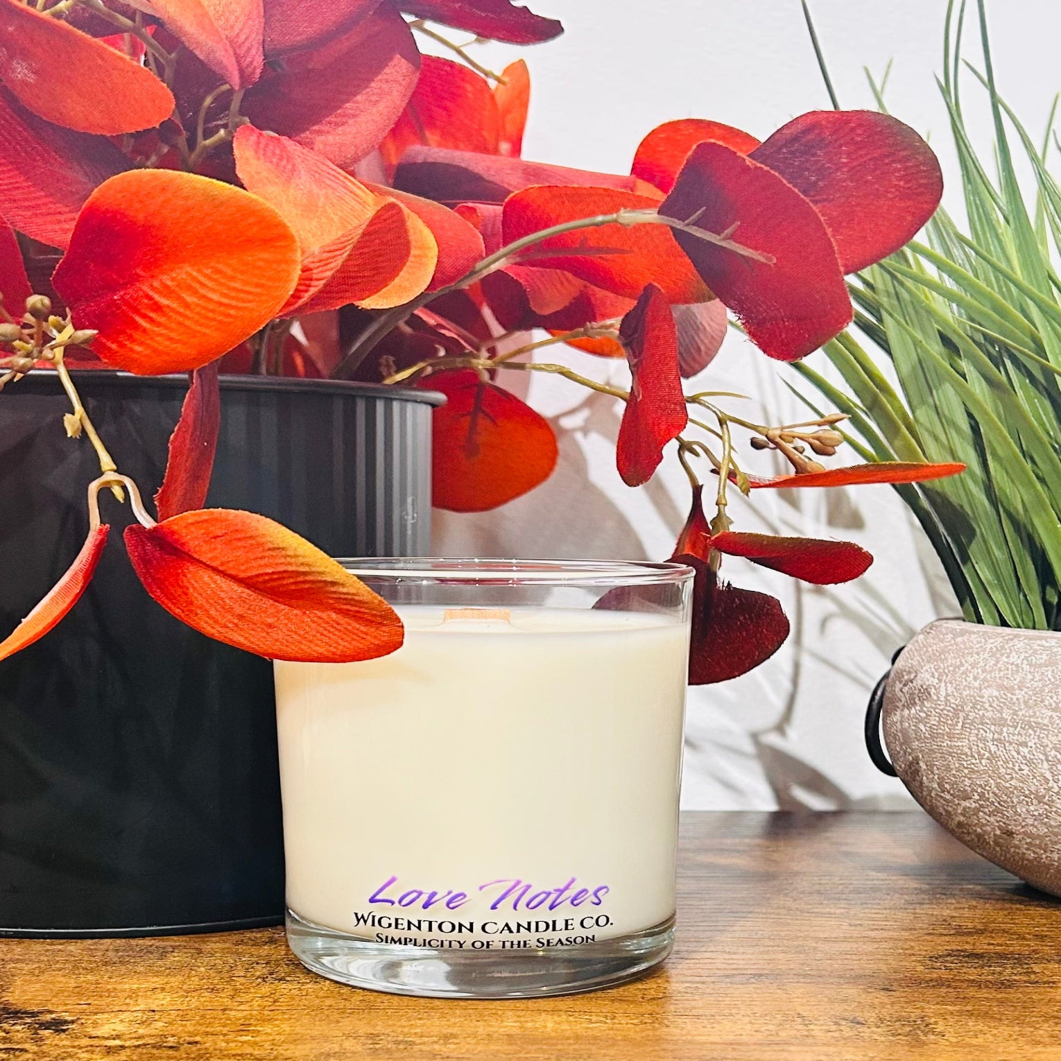 Candle labeled 'Love Notes' by Wigenton Candle Co. with red flowers in the background.